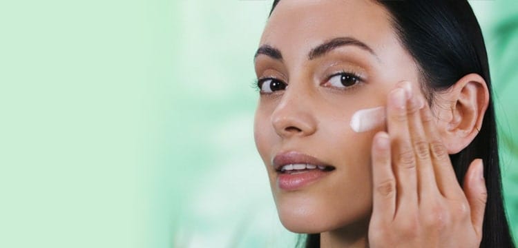 A lady applying a swipe of Origins oil-free moisturizer on her cheek